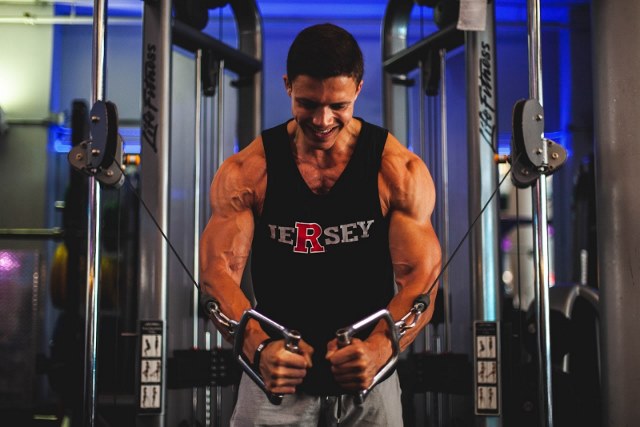 man in black tank top is doing the exercise in gym